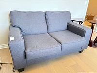 Front angled view of charcoal grey loveseat showing cushions, arms, and feet
