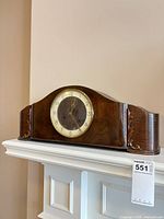 Front view of wooden mantel clock on mantel