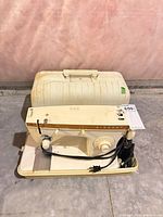 Singer Model 247 sewing machine sitting in base of its plastic case, power cord and foot pedal visible