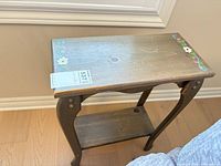 Side view of wooden side table showing floral detail on top and lower shelf