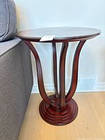 Front view of round cherry pedestal end table beside sofa