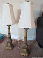 Both matching antiqued resin table lamps with shades displayed side by side