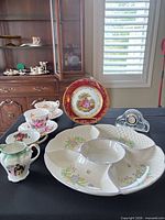 Complete lot showing teacup sets, pitcher, Limoges plate on stand, divided dish and crystal clock