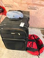 Air Canada suitcase with travel pillow on top and red MEC bag beside