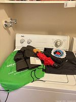All items grouped on washer: two backpacks, two umbrellas, folded hats