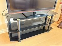 Front view of black glass TV stand with television on top