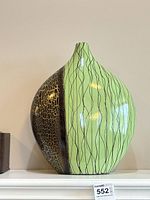 Front view of mint green and brown painted metal vase