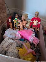 Box containing six dolls and pile of clothing
