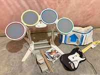 Overview of drum kit, guitar, dance pad, drumsticks, game cases