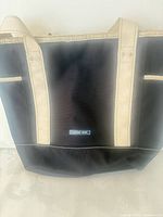 Front view of beige trim canvas tote bag with dark body