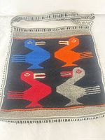 Front view of handwoven wool shoulder bag showing bird motif and strap