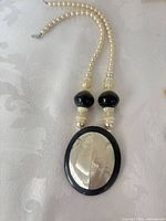 Oval shell pendant necklace with faux pearl strand and black beads