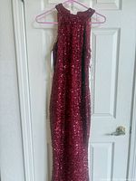 Front view of burgundy sequin evening gown on hanger