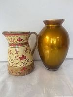 Ceramic floral pitcher next to amber glass vase