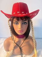 Front view of red felt cowboy hat on mannequin head showing braids, stitching and chin strap