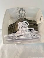 Box containing stack of gray flocked hangers and white hangers