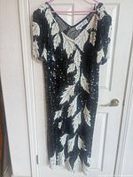 Front view of black silk sequined dress hanging