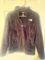 Front view of full-zip The North Face fleece jacket on hanger