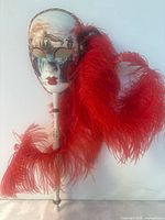 Full view of mask on stick with feather plume
