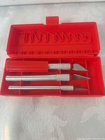 Red plastic box opened showing three aluminum hobby knives