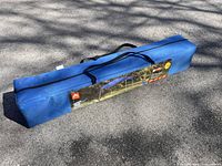 Blue carry case for 10 ft slant-leg canopy lying on pavement