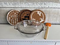 Casserole with lid, three cork trivets, orange spatula grouped together