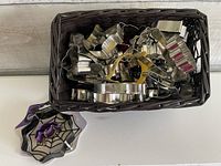 Top view of basket filled with assorted metal cookie cutters and packaged spider web cutter