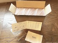 Open box filled with stacks of individually wrapped Pandora ring sizer cards plus two sample cards displayed