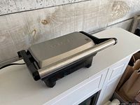 Closed view of appliance showing stainless lid and handle