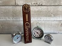 Group shot of Yamaha Clavinova stand with clock and three separate alarm clocks