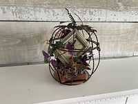 Full view of copper wire pumpkin birdcage with interior decor