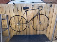 Front view of metal bicycle wall décor on wooden fence