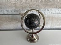 Front view of globe showing black sphere, silver printing, metal stand