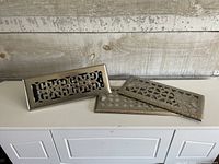 All three metal floor registers displayed together for scale and design comparison