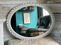 Full view of oval mirror leaning against wall