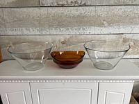 two clear glass bowls flanking amber bowl on cabinet