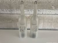 Front view of both frosted glass bottle holders displaying etched motif