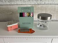 Front view of all four items: seeds box, cat treats jar, Good Natured Fossil tin, nutmeg grater