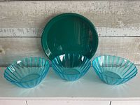 Three blue bowls and one green tray displayed upright