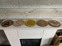 All five cork trivets lined up on mantle