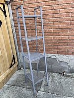 Full view of tall grey metal shelving unit, four mesh shelves