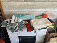 Assorted textiles and packaged sewing notions stacked on fireplace top