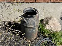 Front view of rusty metal milk can showing body, mouth and handles