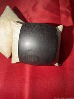 Front view of black wooden bangle on display cushion