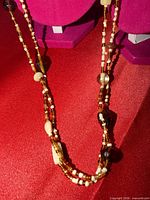 Full view of long brown and cream bead necklace laid out