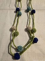 Necklace section showing beaded spheres and green seed bead strand