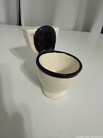 Front angled view showing toilet-shaped ceramic dish with black seat
