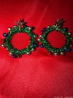 Front view of both wreath earrings on red background