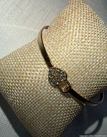 Bangle on display pillow showing metal finish and heart charm with stones