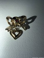 Front view of gold-tone bow brooch with heart charm